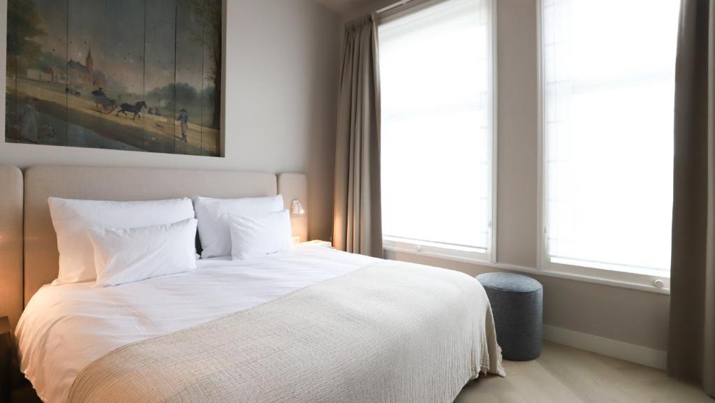 a bedroom with a white bed and a painting at Dam Residence Boutique Hotel Amsterdam - Zaandam in Zaandam