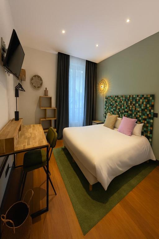 a bedroom with a bed and a desk and a television at Urban Jungle Hôtel Orleans in Orléans