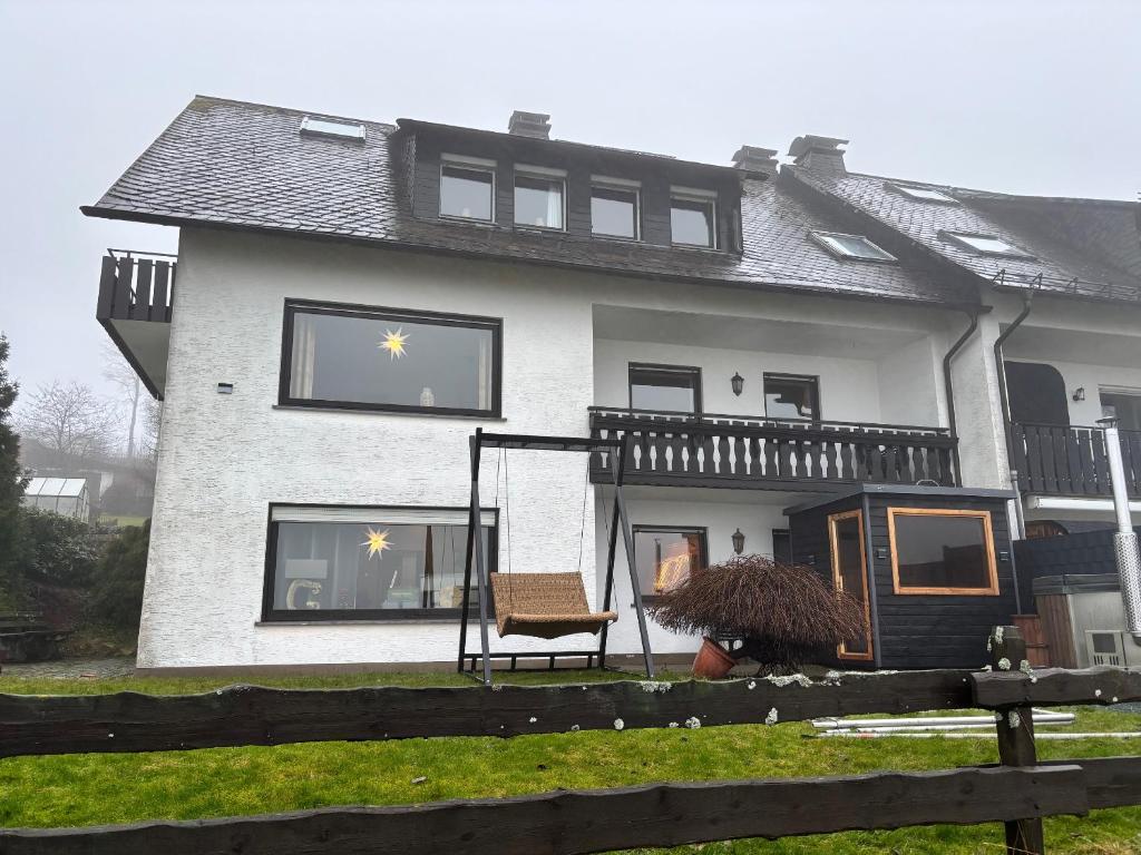 ein Haus mit Fenstern und einem Stuhl davor in der Unterkunft Haus Aktiv Top2 in Winterberg