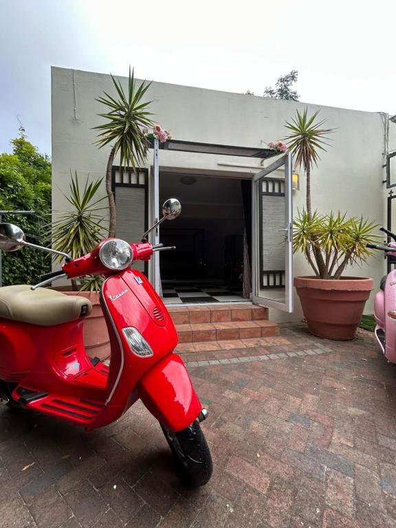 a red scooter parked in front of a house at Innessfree Cottage in Doordrift