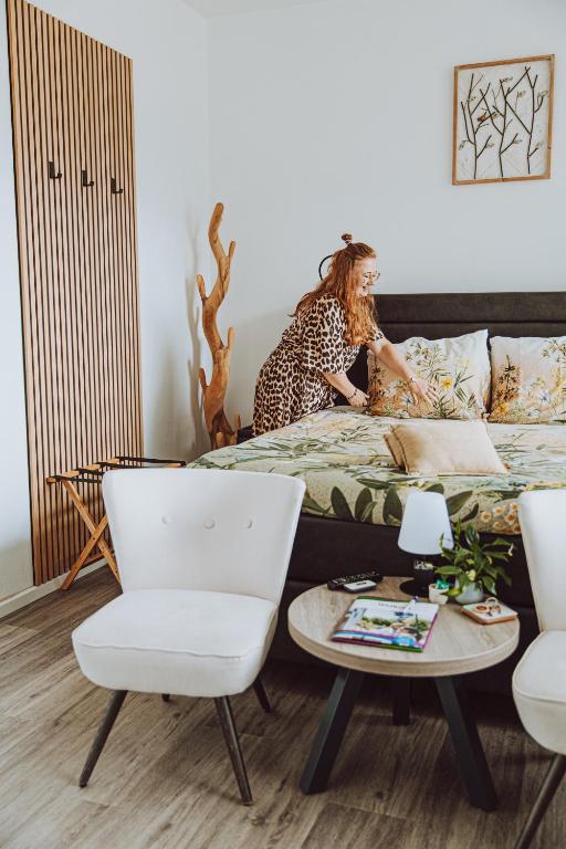 a woman sitting on a bed in a room at Bed & Breakfast Het Vinkenest Nijverdal in Nijverdal