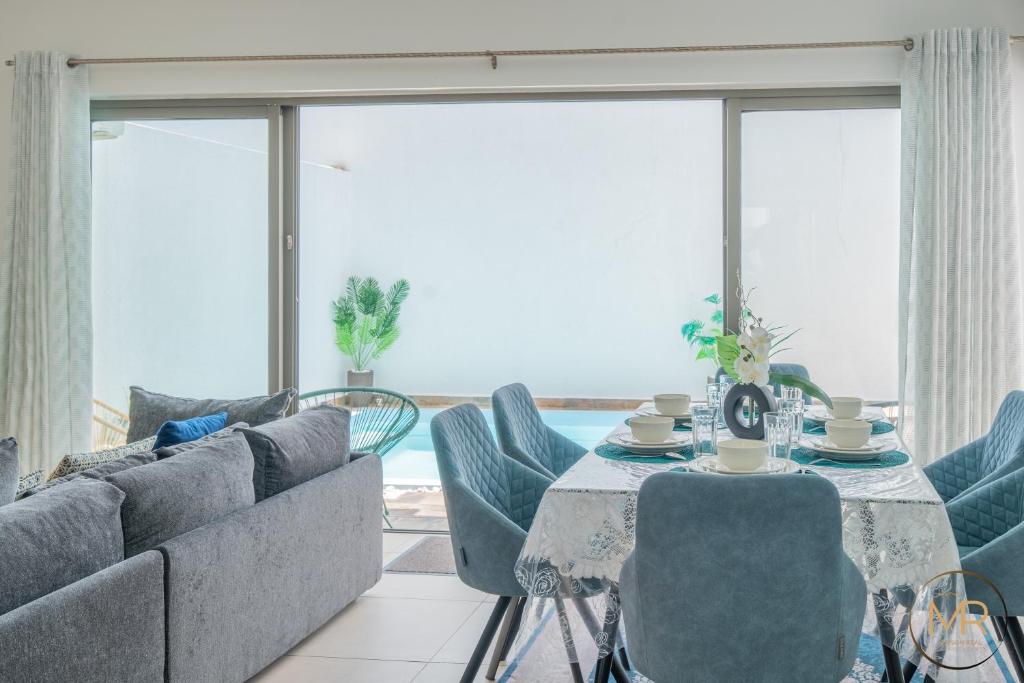 a living room with a couch and a table and chairs at Azure 4 Bedrooms Haven Retreat: Where Tranquility Meets Turquoise Waters, Flic en Flac Mauritius in Flic-en-Flac