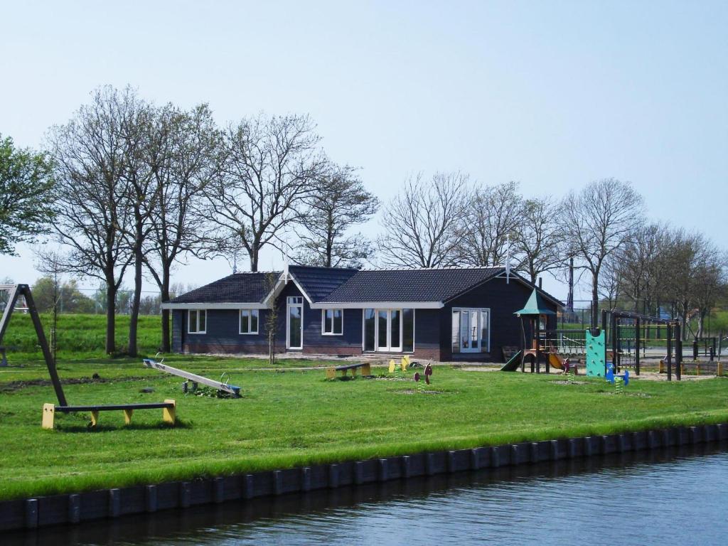 a house with a playground next to the water at Group accommodation De Beemster with Sauna | 14 persons in West-Graftdijk