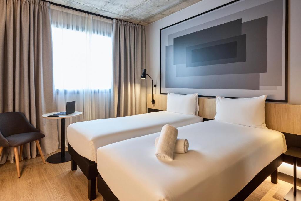 a hotel room with two beds and a tv at ibis Madrid Norte Las Tablas in Madrid
