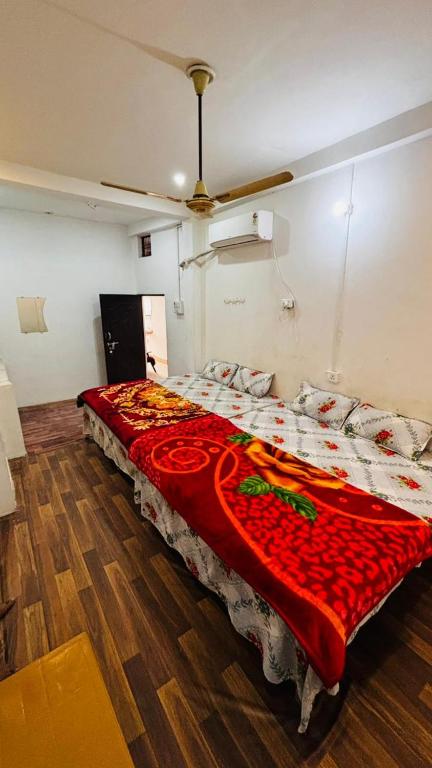 a bedroom with a large bed with a red blanket at Radha Krishna Paying Guest House in Ayodhya