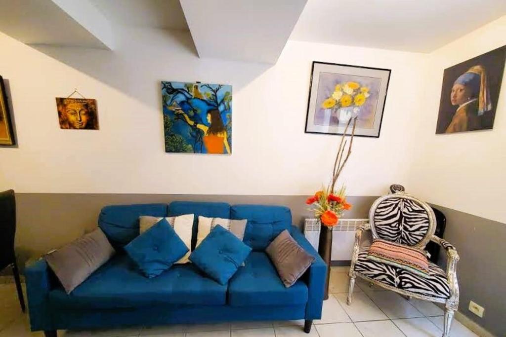 eine blaue Couch und ein Stuhl im Wohnzimmer in der Unterkunft L'Occitane Maison de village climatisée in Lapalme