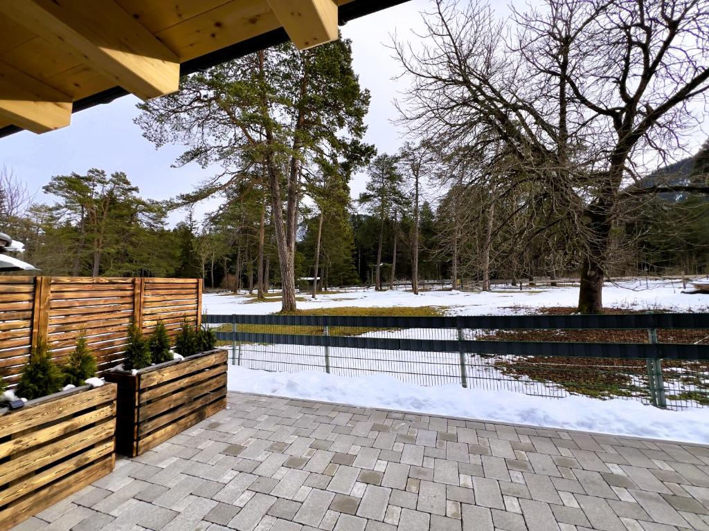 a pavilion with a fence and a pond with snow at LechHuamat in Weissenbach am Lech