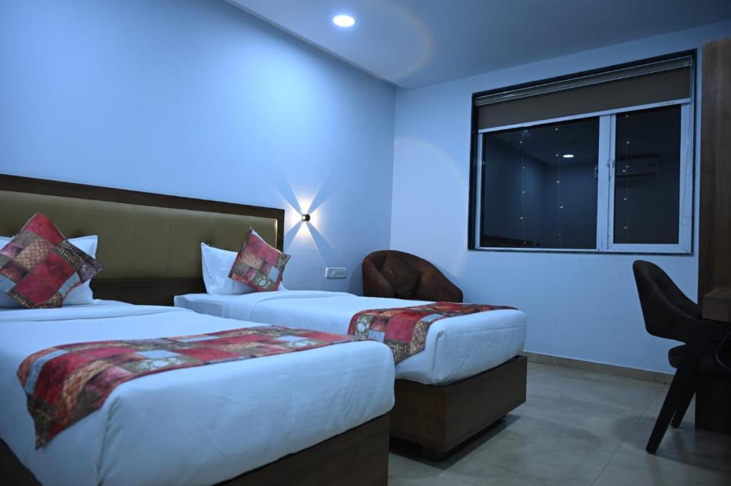 Una habitación de hotel con dos camas y una ventana. en Hotel Alento, en Jamnagar