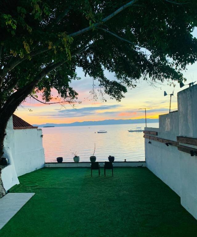 a patio with a view of the water at sunset at Oceanfront Scuba Villa in Moalboal