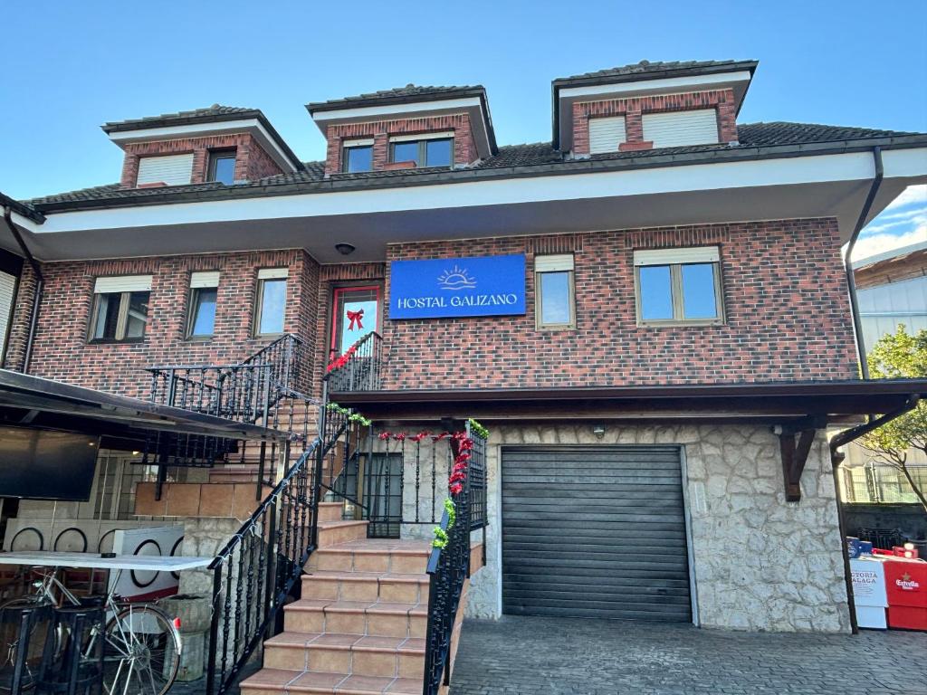 Un edificio de ladrillo con garaje y un cartel azul. en Hospedaje Galizano, en Galizano