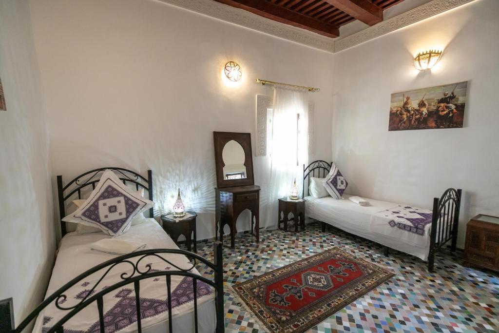 een slaapkamer met 2 bedden, een tafel en een spiegel bij Dar El Kendil in Fès