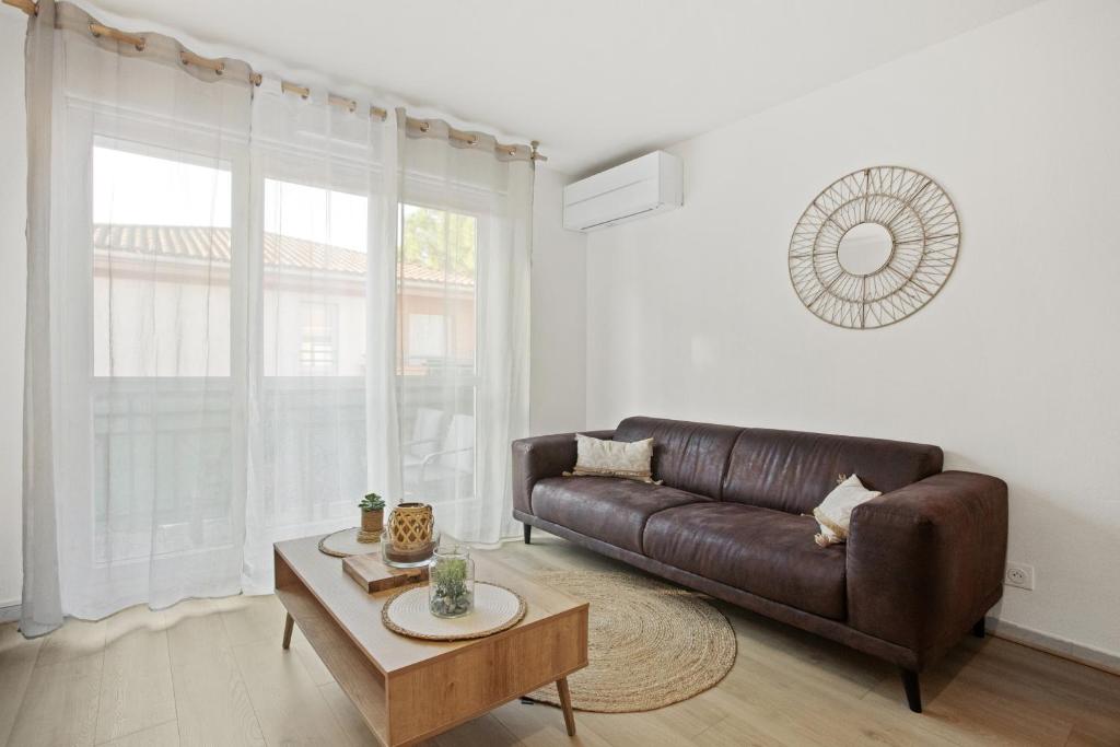 ein Wohnzimmer mit einem braunen Sofa und einem Tisch in der Unterkunft Un Havre De Paix in Fréjus