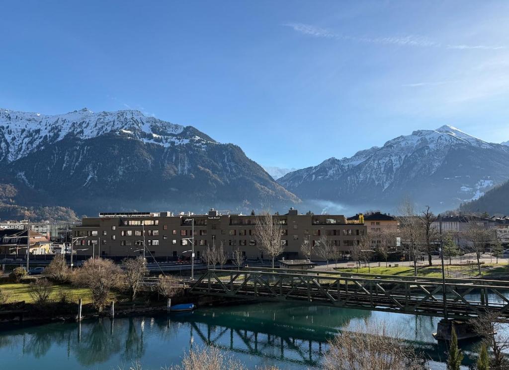 a bridge over a river with mountains in the background at River-2 with Iconic Jungfraujoch View in Interlaken