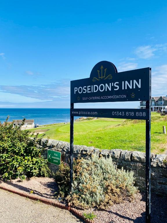 a sign in front of a beach with the ocean at Poseidon's in Lossiemouth