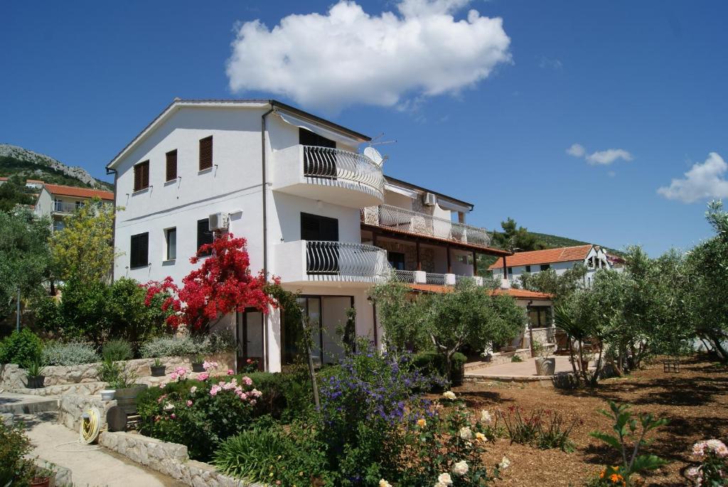 a white building with a garden in front of it at Apartmani Braco Caratan in Zavala