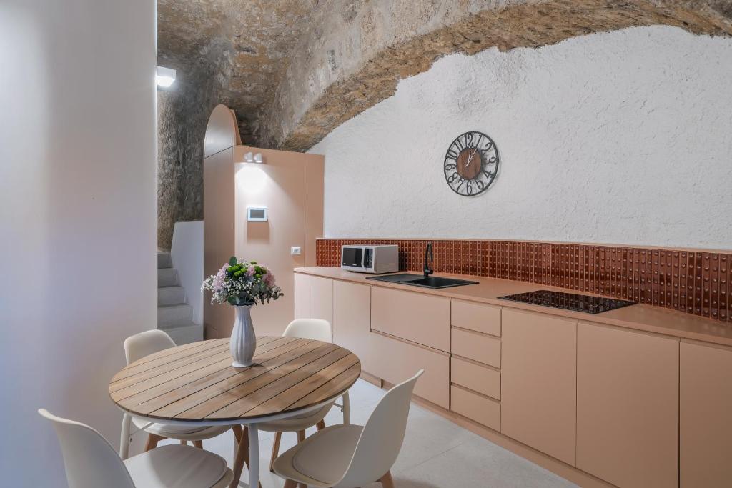 a kitchen with a wooden table and white chairs at L'Appoggio in Castellammare di Stabia