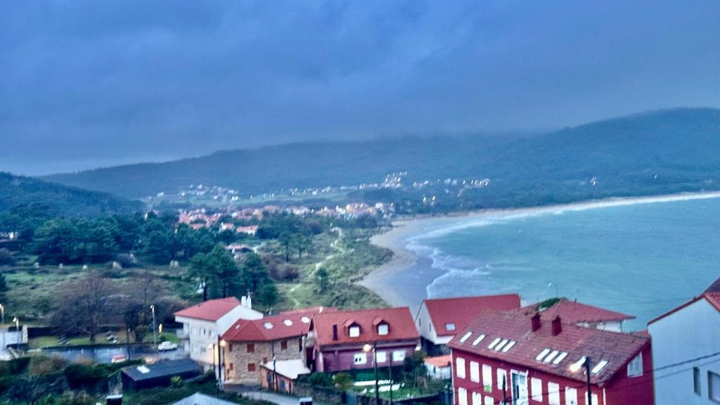 Una vista de una playa con casas y el océano. en Atico Finisterre, en Finisterre
