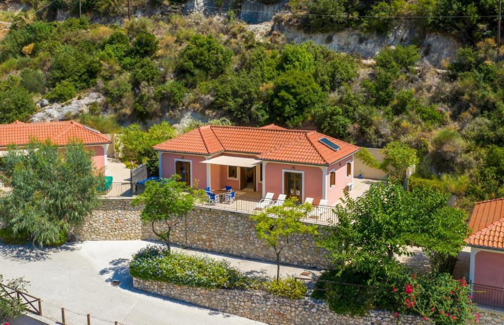 una pequeña casa rosa con una pared de piedra en Elia Beach Villa, en Stavros