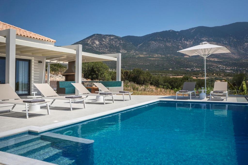a swimming pool with chairs and an umbrella at Villa Stellina in Karavádhos