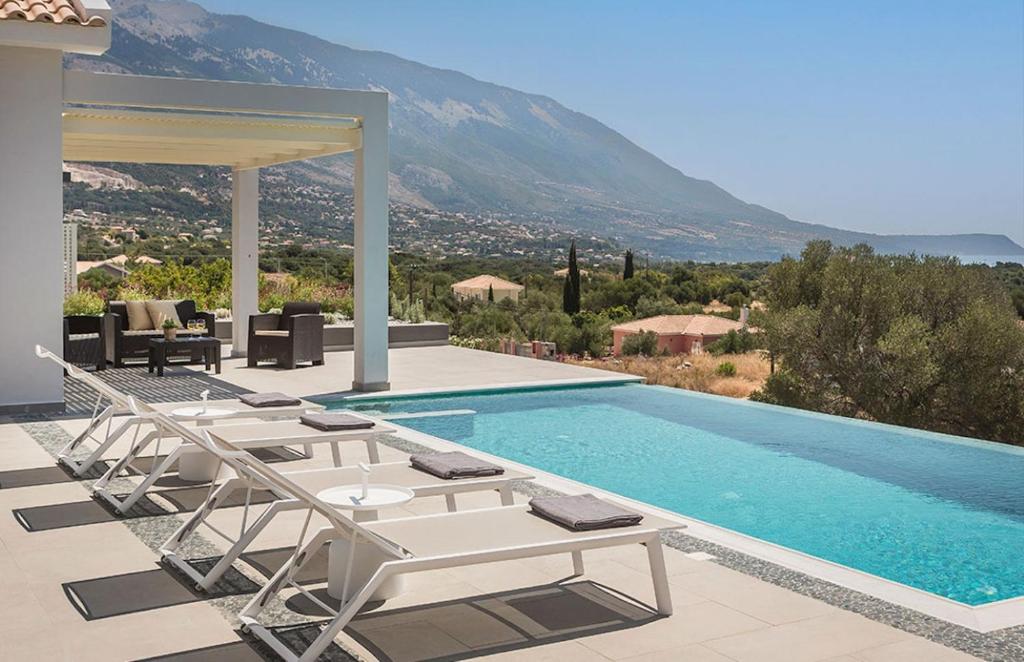 a swimming pool with lounge chairs and a villa at Villa Anelle in Karavádhos