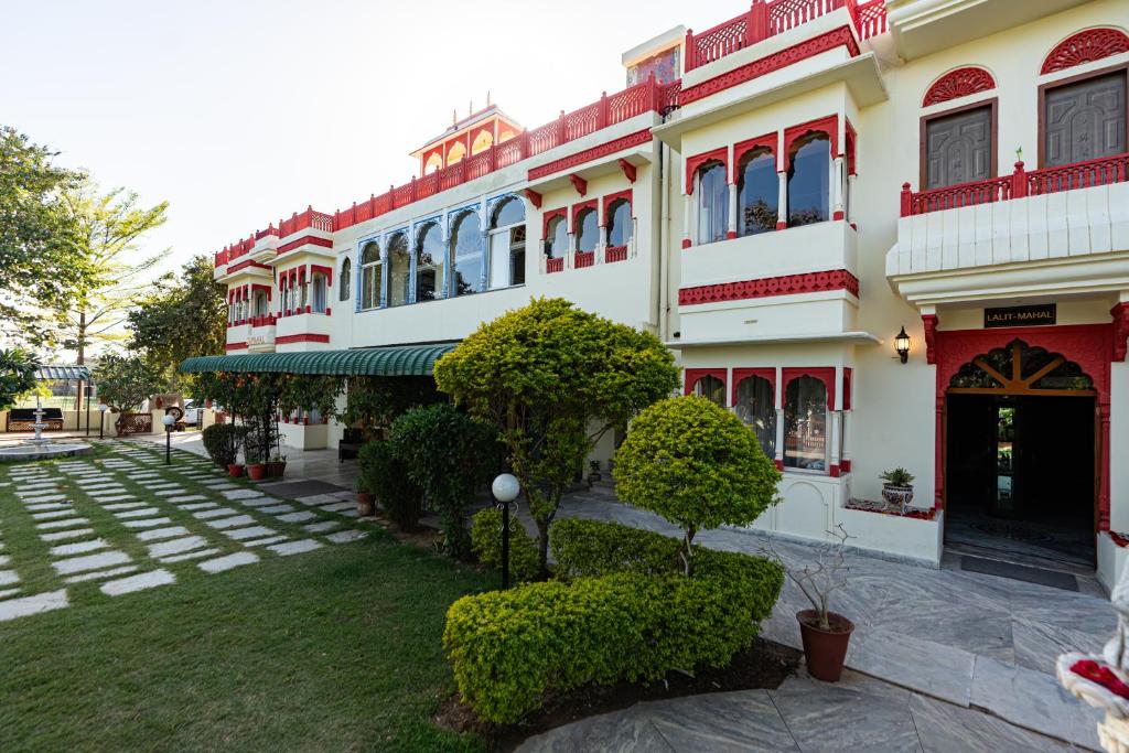 a large white building with red windows and a yard at Chomu Bagh Hotel & Resorts in Chomu in Jaipur