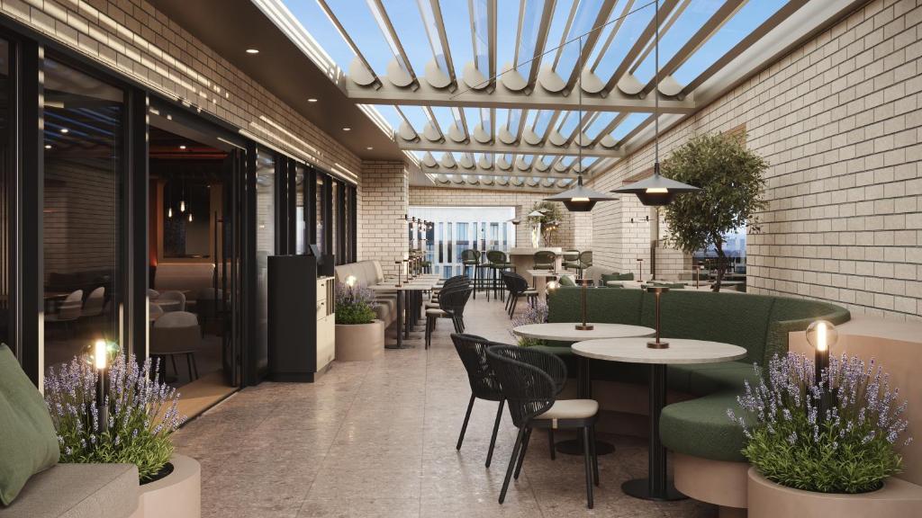 a restaurant with tables and chairs and a glass ceiling at Bergmann's-Das Hotel in Osnabrück