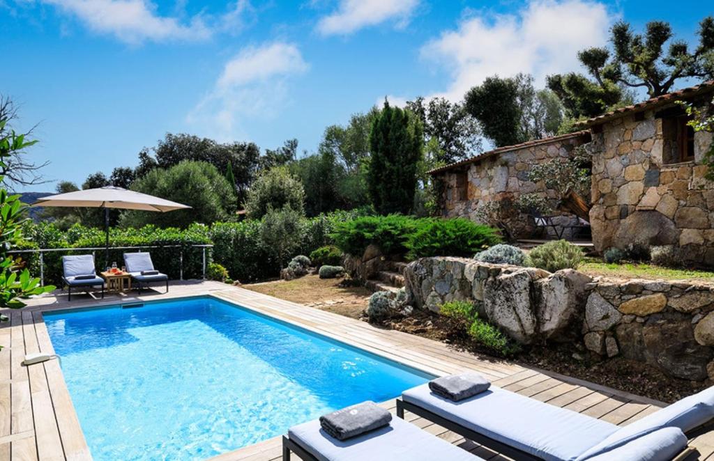 een zwembad in een tuin met een stenen muur bij U Caseddu in Sotta