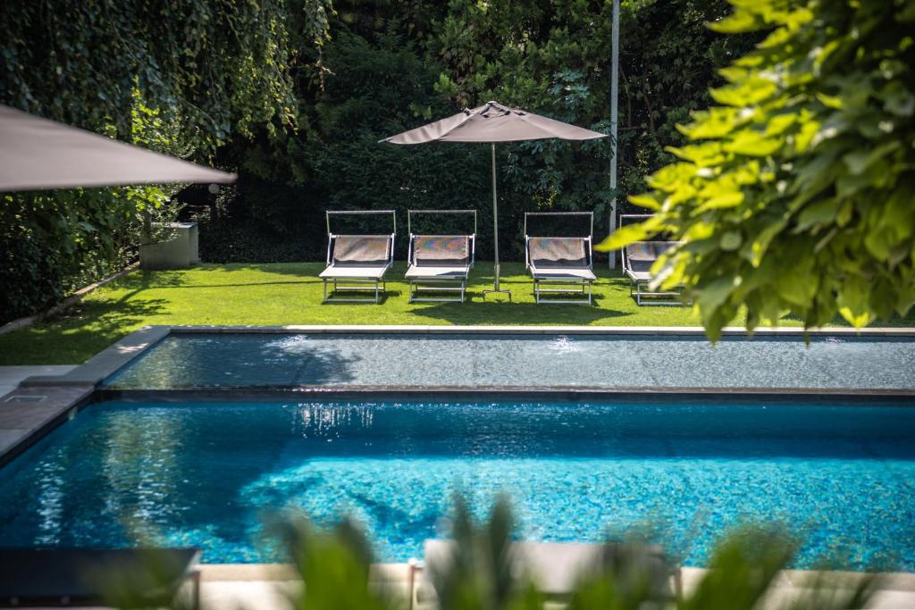 een zwembad met twee stoelen en een parasol bij goldfinger + suites in Lana