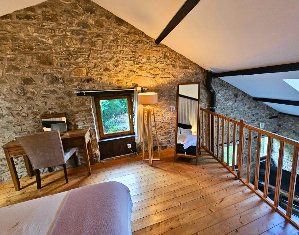 een woonkamer met een stenen muur en een bureau bij Le Cosy - Domaine du Vertendre in Saint-Yrieix-la-Perche