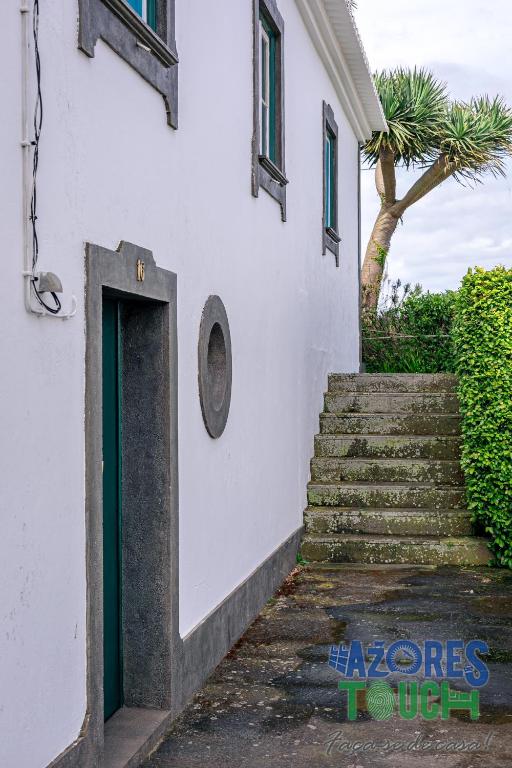 a stairway leading up to a white building with a door at Hospedaria casa D'Avo in Praia da Vitória