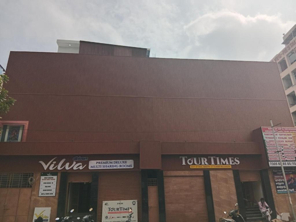 a brown building with a tour times sign on it at Vilva Premium Multi Sharing Rooms in Madurai