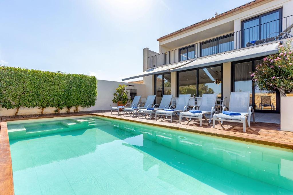 een zwembad met stoelen en een huis bij Casa Reiet by dracmallorca in Santanyi