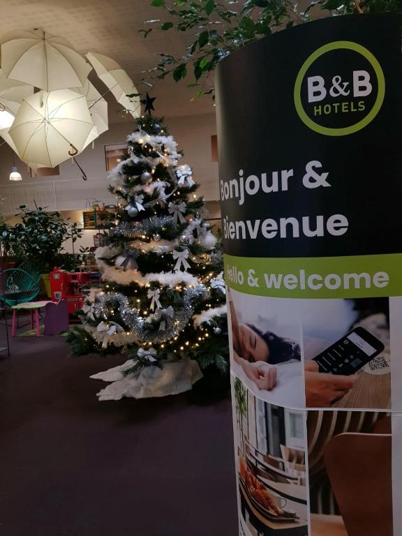 a christmas tree in a room with a book at B&B HOTEL Aurillac Le Lioran in Aurillac