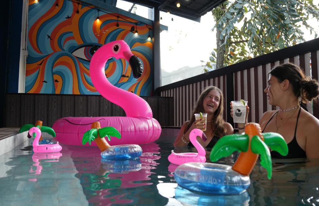two women in a pool with pink flamingos in the water at The Hangout Hostel Ao Nang in Ao Nang Beach