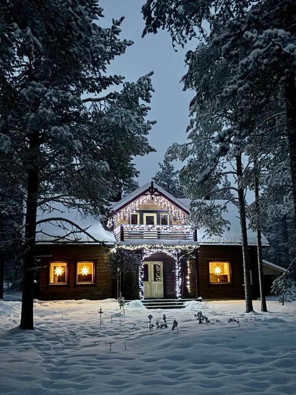 a house with christmas lights on it in the snow at Pine Forest Hideout - Villa Tapiontytär in Kittilä