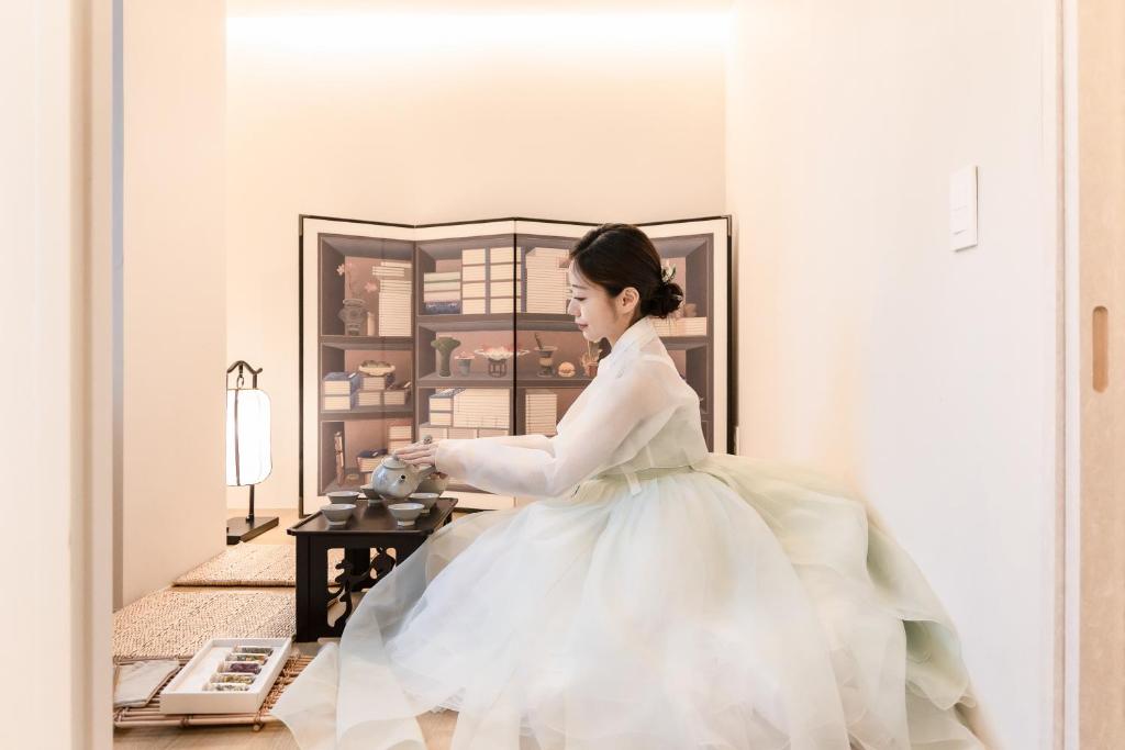 a woman in a white dress sitting in a room at 율 한옥 호텔 in Samgong