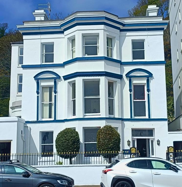 a white house with cars parked in front of it at Kings House in Douglas