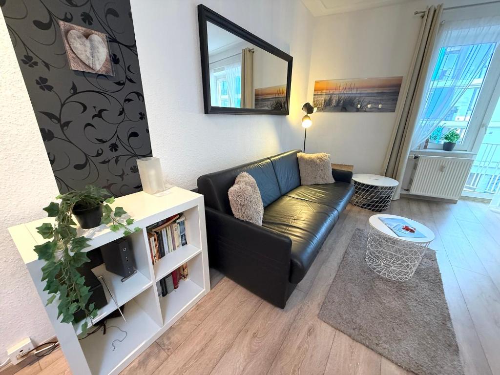 a living room with a black couch and a mirror at Haus Solymar, Whg 44 in Grömitz