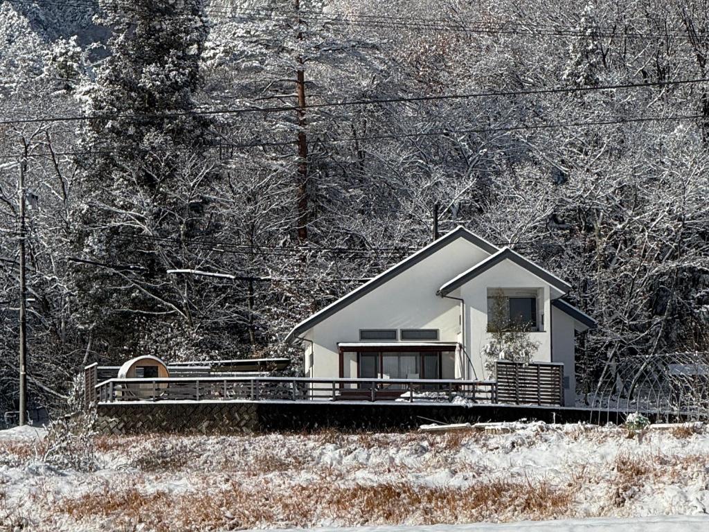 a small white house in the middle of a forest at 一棟貸切Azumino36Stay 安曇野の静かな隠れ家 貸切サウナ BBQ 絶景テラス in Azumino