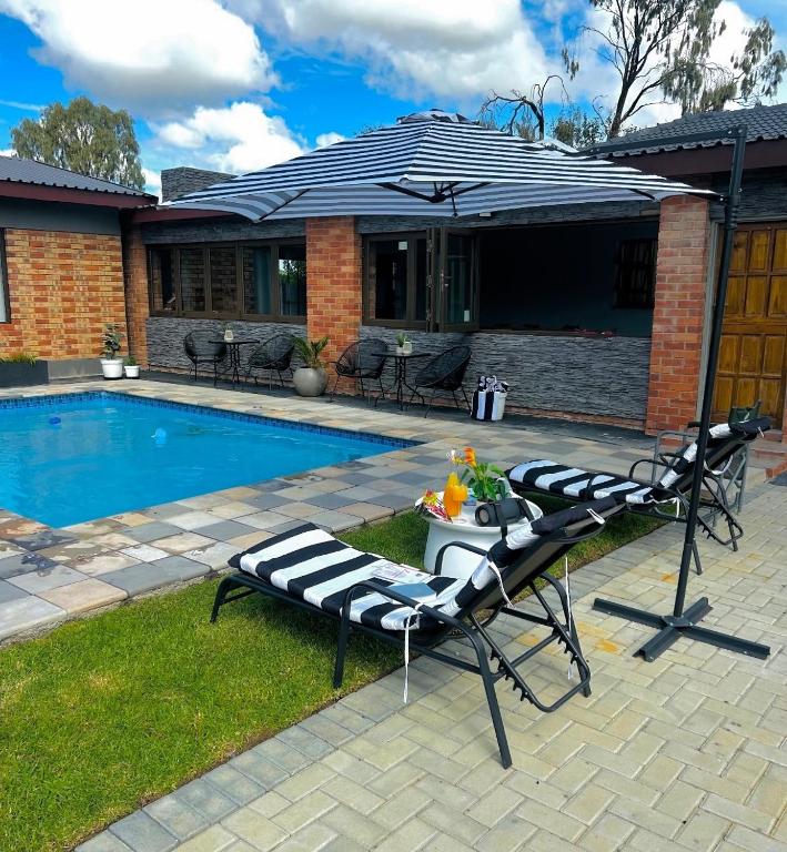a pool with two chairs and a table next to a house at Hope Villa Luxury Accomodation in Odendaalsrus