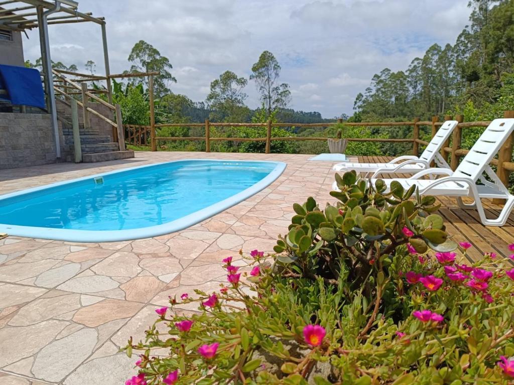 a swimming pool with two lawn chairs and flowers at CascataDiamantePousada in Laurentino