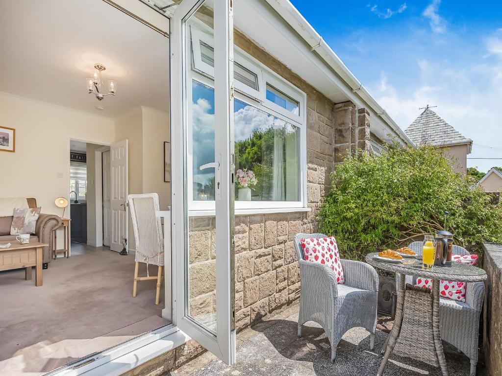 Un patio con una mesa y sillas y una ventana. en Black Hill View, en Manaton
