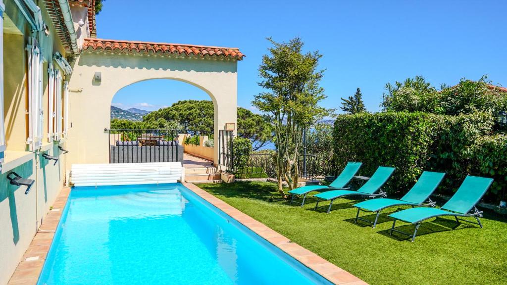 een zwembad met blauwe stoelen naast een huis bij Hôtel Villa Maya - Golfe de Saint-Tropez in Saint-Tropez
