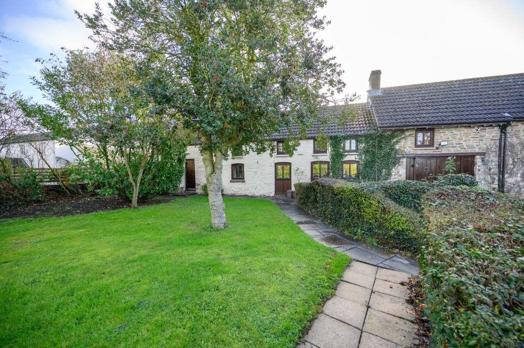 a house with a tree in front of a yard at Laurel Cottage - Sleeps 5 - Gardens - Relaxing Rural Home by STAE-Homes in Magor