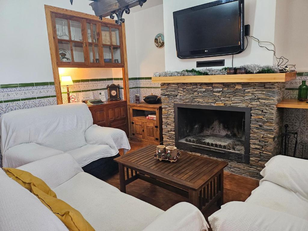 un soggiorno con divani e camino con TV di Finca el Berezal ad Aracena
