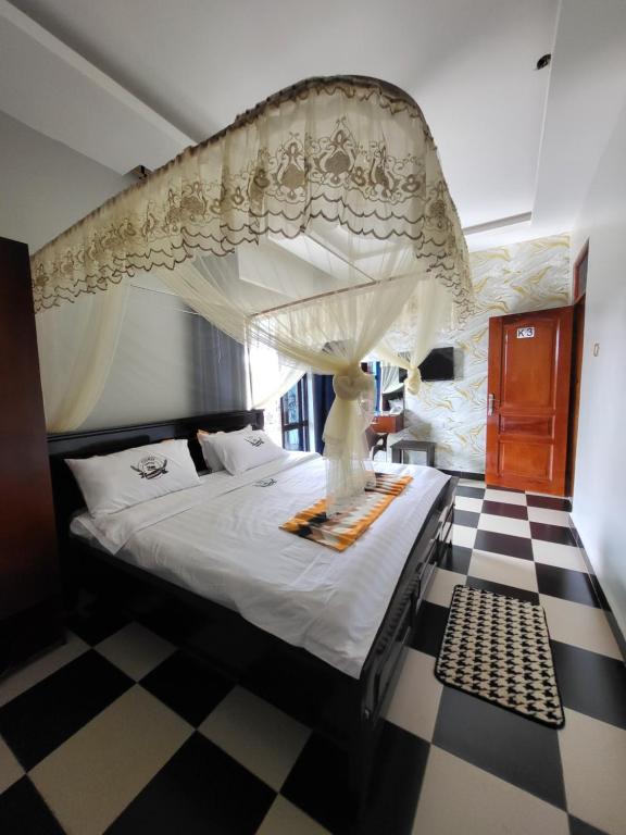 a bedroom with a canopy bed with a checkered floor at Tigris Residence in Bulenga