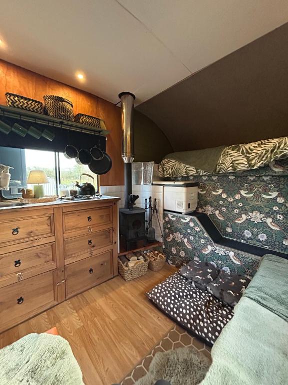 a room with a bed and a kitchen with a stove at Flowerdew Farm in Puncknowle