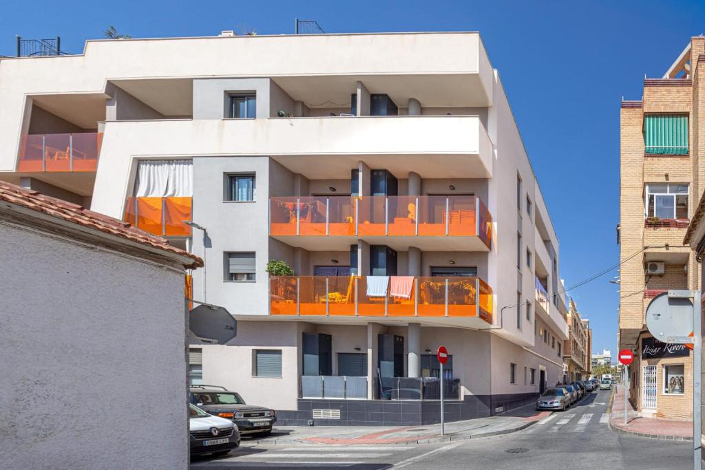 ein Apartmenthaus mit orangefarbenen Balkonen an einer Stadtstraße in der Unterkunft Casa Arne in Torrevieja
