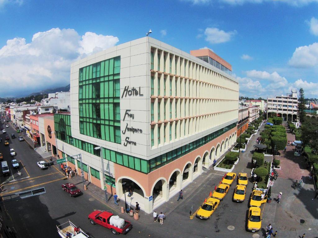 un grand bâtiment avec des voitures garées dans une rue dans l'établissement Hotel Fray Junipero Serra, à Tepic