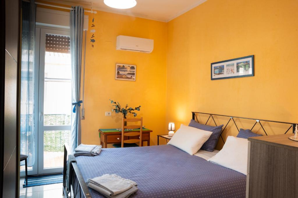 a bedroom with yellow walls and a bed with blue sheets at La Playa di Ponente in Cagliari